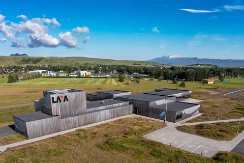 LAVA Centre on a beautiful summer day with Eyjafjallajökull volcano, Katla volcano, Tindfjoll volcano, Mt. Thrihyrningur and the town of Hvolsvollur in the background.