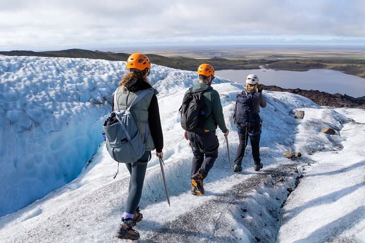 Hikers explore the icy terrain of a glacier in Vatnajokull National Park, carefully following each other in a line.