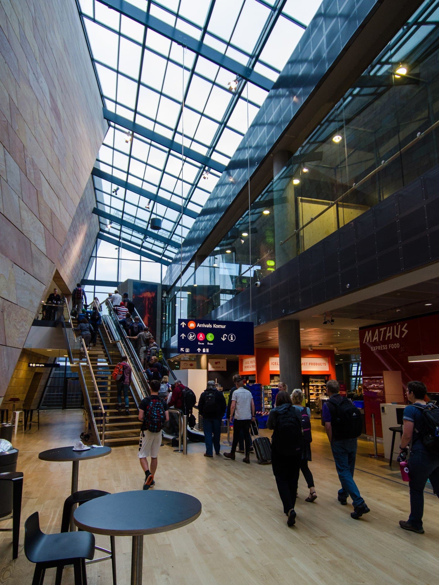 Arrivals hall at Keflavík Airport with travelers and the Komur / Arrivals sign