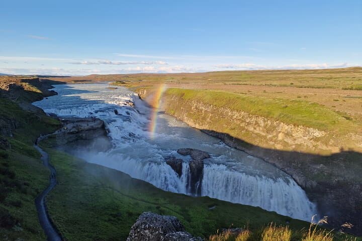 a picture of the Gullfoss waterfalls with a rainbow from a top viewdeck during sunset