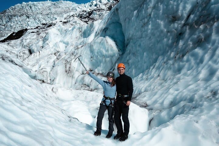 A couple hikes together across a frozen Skaftafell glacier in Iceland.