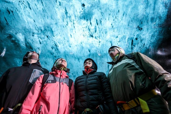 A group of visitors look up in wonder at the ceiling of an ice cave.